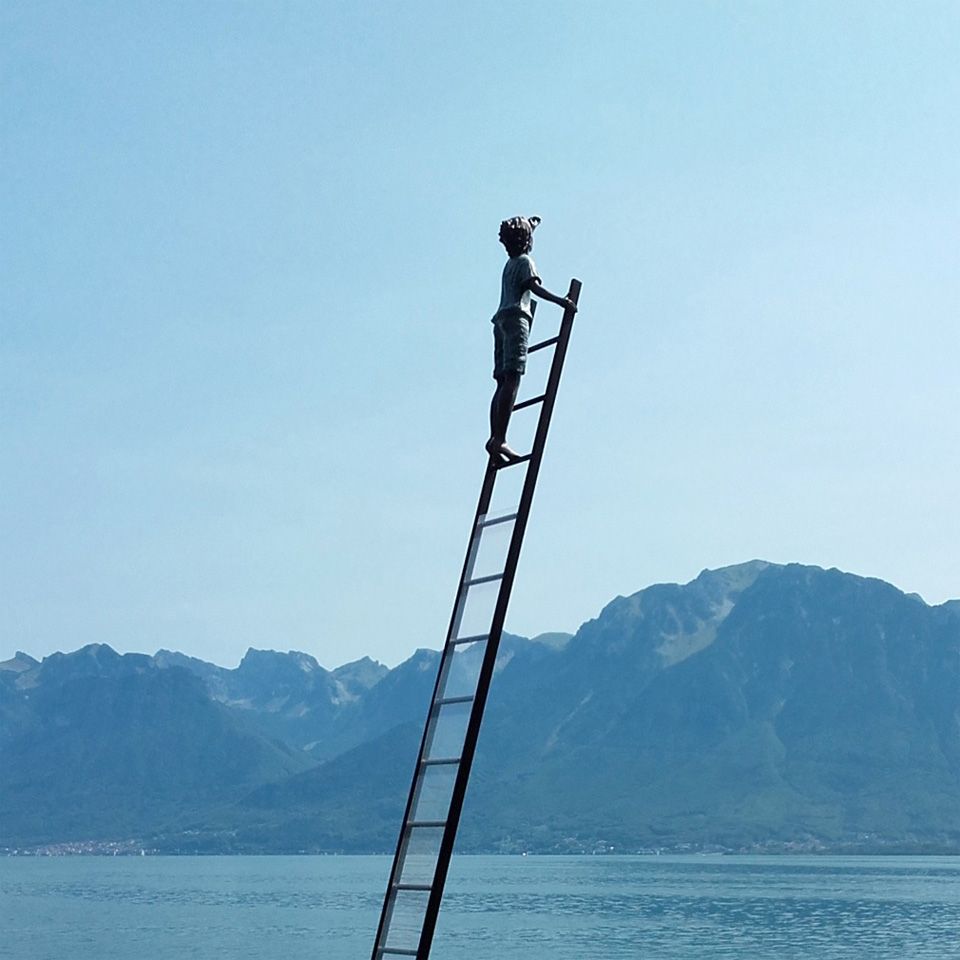 Een figuur op een ladder met uitzicht op de bergen